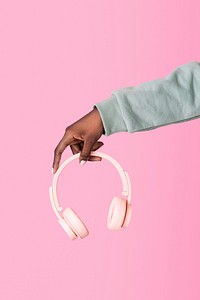 Hand holding pink headphones with pink background