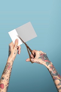 Hands with tattooed holding scissors cutting paper