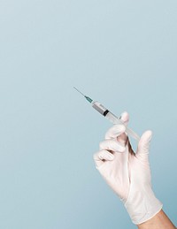 Hand wearing a white glove holding a syringe
