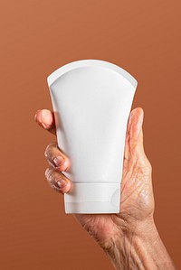Hand holding a facial cream tube container