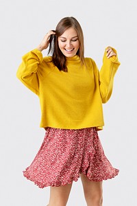 Cheerful woman wearing a mustard yellow sweater on a red flower dress