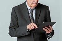 Senior businessman in a suit using a digital tablet