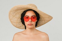 Bare chested woman wearing a big round hat and red vintage heart-shaped sunglasses