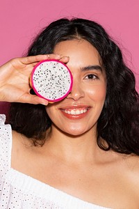 Woman covering her eyes with a sliced dragon fruit