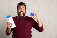 Excited Indian man holding a credit card and fligh tickets