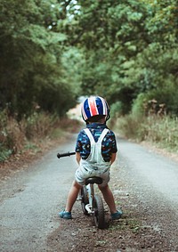 Little boy learning how to ride a bike in the forest