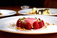 Small red desert surrounded by raspberries on a white plate with other desserts in the background. Original public domain image from <a href="https://commons.wikimedia.org/wiki/File:Gourmet_Dessert_(Unsplash).jpg" target="_blank" rel="noopener noreferrer nofollow">Wikimedia Commons</a>