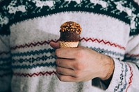Person wearing a cozy sweater and eating a drumstick ice cream cone. Original public domain image from <a href="https://commons.wikimedia.org/wiki/File:Cold_Treats_(Unsplash).jpg" target="_blank" rel="noopener noreferrer nofollow">Wikimedia Commons</a>