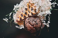 An overhead shot of a chocolate chip muffin next to a piece of pie decorated with elderflowers. Original public domain image from <a href="https://commons.wikimedia.org/wiki/File:Spring_Desserts_(Unsplash).jpg" target="_blank" rel="noopener noreferrer nofollow">Wikimedia Commons</a>