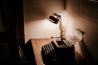 A typewriter and a lamp sitting on a desk Bowen Island. Original public domain image from <a href="https://commons.wikimedia.org/wiki/File:Typewriter_(Unsplash).jpg" target="_blank" rel="noopener noreferrer nofollow">Wikimedia Commons</a>