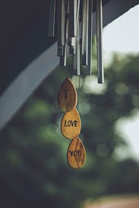 Wind chimes hanged outdoors with three suspended plates reading “I love you”. Original public domain image from Wikimedia Commons