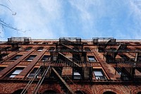 Ground view of a red brick apartment building and fire escape in New York City. Original public domain image from Wikimedia Commons