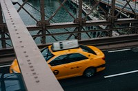 A high view of a yellow taxi cab driving on a bridge. Original public domain image from <a href="https://commons.wikimedia.org/wiki/File:Yellow_taxi_cab_from_above_(Unsplash).jpg" target="_blank" rel="noopener noreferrer nofollow">Wikimedia Commons</a>
