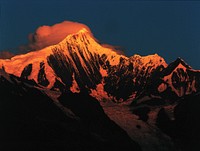 Orange sun rays illuminate a snow-capped mountain during sunrise. Original public domain image from Wikimedia Commons