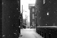 View from an alleyway in a city with snow falling around houses with a family walking through the street. Original public domain image from <a href="https://commons.wikimedia.org/wiki/File:A_True_Family_Connection_(Unsplash).jpg" target="_blank" rel="noopener noreferrer nofollow">Wikimedia Commons</a>