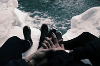 Couple with hands clasped while sitting on icy mountaintop overlooking water. Original public domain image from Wikimedia Commons