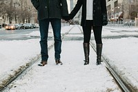 On train tracks covered in snow, two lovers stand holding hands. Original public domain image from <a href="https://commons.wikimedia.org/wiki/File:Put_your_boots_on_(Unsplash).jpg" target="_blank" rel="noopener noreferrer nofollow">Wikimedia Commons</a>