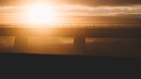 A hazy golden sunset puts a modern bridge into silhouette at Rangitata River.. Original public domain image from Wikimedia Commons