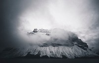 An ominous shot of a tall mountain shrouded in thick clouds in Banff. Original public domain image from Wikimedia Commons
