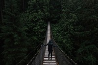 A female walks across the bridge at Lynn Canyon Park in North Vancouver, British Columbia. Original public domain image from <a href="https://commons.wikimedia.org/wiki/File:A_girl_walking_across_a_bridge_(Unsplash).jpg" target="_blank" rel="noopener noreferrer nofollow">Wikimedia Commons</a>