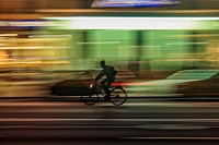 Long exposure photo of a man on a bicycle at night in Albenga, Liguria, Italy.. Original public domain image from Wikimedia Commons