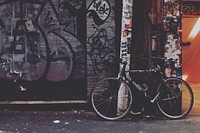 Bike leaning against post with stickers and graffiti on urban wall in Melbourne. Original public domain image from Wikimedia Commons