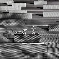 A gray bicycle parked on a gray latticework surface. Original public domain image from <a href="https://commons.wikimedia.org/wiki/File:The_Bike_(Unsplash).jpg" target="_blank" rel="noopener noreferrer nofollow">Wikimedia Commons</a>