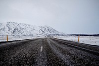 A dark road veers towards a snowy mountain in Iceland. Original public domain image from <a href="https://commons.wikimedia.org/wiki/File:The_road_near_mountains_(Unsplash).jpg" target="_blank" rel="noopener noreferrer nofollow">Wikimedia Commons</a>