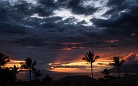 A cloudy sunset over silhouetted palm trees and hills at Wailea-Makena. Original public domain image from Wikimedia Commons