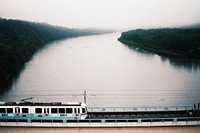 Public transport train on a bridge crosses the river on a misty and cloudy day. Original public domain image from Wikimedia Commons