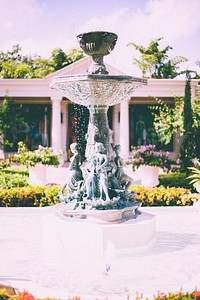 An ornate fountain in the middle of a garden in front of a classical building. Original public domain image from Wikimedia Commons