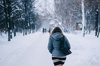 A woman wearing a skirt and jacket, walking through the snow on a treed road. Original public domain image from <a href="https://commons.wikimedia.org/wiki/File:Woman_walking_winter_road_(Unsplash).jpg" target="_blank" rel="noopener noreferrer nofollow">Wikimedia Commons</a>