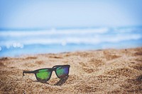 Colorful reflections in a pair of sunglasses left on a golden beach. Original public domain image from Wikimedia Commons