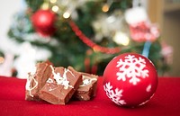 Fudge and a Christmas ornament with a Christmas tree in the background. Original public domain image from <a href="https://commons.wikimedia.org/wiki/File:Christmas_cookies_(Unsplash).jpg" target="_blank" rel="noopener noreferrer nofollow">Wikimedia Commons</a>