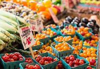 Red and orange cherry tomatoes and other vegetables on a market stall. Original public domain image from Wikimedia Commons