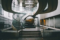 A large metal sphere near a winding staircase in a building. Original public domain image from <a href="https://commons.wikimedia.org/wiki/File:Metal_sphere_under_a_staircase_(Unsplash).jpg" target="_blank" rel="noopener noreferrer nofollow">Wikimedia Commons</a>