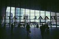 Passengers are at the entrance of the Rotterdam Centraal Station with the Rotterdam cityscape in view.. Original public domain image from <a href="https://commons.wikimedia.org/wiki/File:Silhouettes_Rotterdam_station_(Unsplash).jpg" target="_blank" rel="noopener noreferrer nofollow">Wikimedia Commons</a>