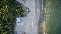 A drone shot of an empty beach lined with deck chairs and umbrellas. Original public domain image from <a href="https://commons.wikimedia.org/wiki/File:Empty_beach_from_above_1_(Unsplash).jpg" target="_blank" rel="noopener noreferrer nofollow">Wikimedia Commons</a>