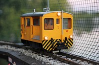 Yellow miniature railcar on a track with gravel and controls besides a wire fence. Original public domain image from <a href="https://commons.wikimedia.org/wiki/File:Yellow_toy_train_(Unsplash).jpg" target="_blank" rel="noopener noreferrer nofollow">Wikimedia Commons</a>