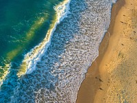 Drone view of ocean waves crashing on the sand beach at Roker Beach. Original public domain image from <a href="https://commons.wikimedia.org/wiki/File:Summer_sunrise_waves_(Unsplash).jpg" target="_blank" rel="noopener noreferrer nofollow">Wikimedia Commons</a>