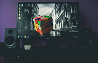 Colorful rubik's cube floats in front of computer monitor and speakers. Original public domain image from Wikimedia Commons