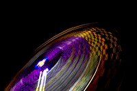 A blurred shot showcasing colorful light trails from a spinning amusement park ride. Original public domain image from Wikimedia Commons