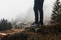 Person wearing jeans and casual sneakers atop a hill near cottages. Original public domain image from Wikimedia Commons