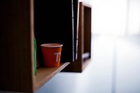 Orange T cup on a wood bookshelf at home. Original public domain image from <a href="https://commons.wikimedia.org/wiki/File:Cup_on_a_Shelf_(Unsplash).jpg" target="_blank" rel="noopener noreferrer nofollow">Wikimedia Commons</a>