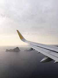 A view from an airplane window on the surface of the ocean with rocky islands jutting out of the water. Original public domain image from <a href="https://commons.wikimedia.org/wiki/File:Balearic_Islands,_Spain_(Unsplash).jpg" target="_blank" rel="noopener noreferrer nofollow">Wikimedia Commons</a>