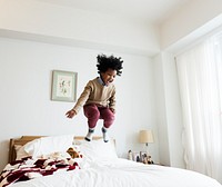 Young happy kid having fun jumping up and down on a bed