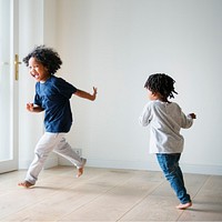 Two black kids playing and chasing each other in an empty room