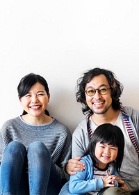Smiling Japanese family with a daughter sitting on the floor text space