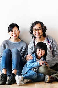 Smiling Asian family with a daughter sitting on the floor