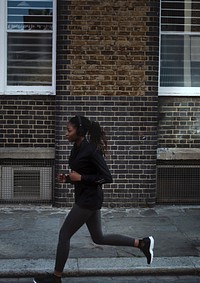 Woman listening to music while jogging in a city